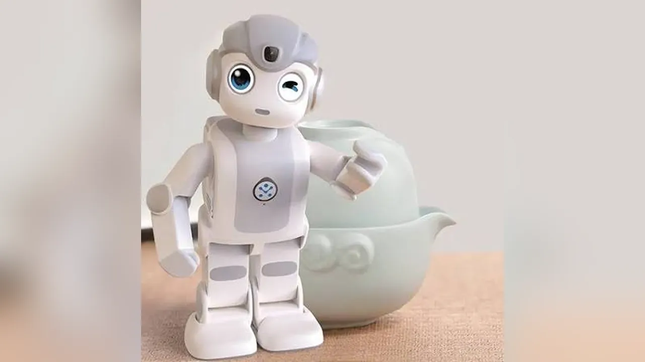 Small white humanoid robot winking next to a pale green teapot on a table, a long way from a factory floor