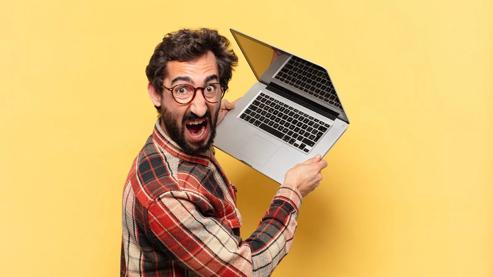 Wild-eyed developer holding a laptop overhead — illustrating what it looks like to hand your business software to someone who codes but doesn't build software